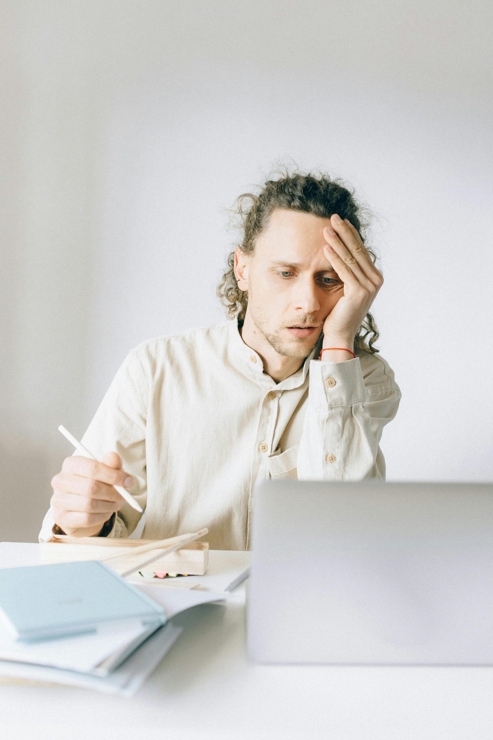 eune entrepreneur stressé devant un ordinateur, entouré de documents administratifs, symbolisant la charge mentale liée à la création d'entreprise.